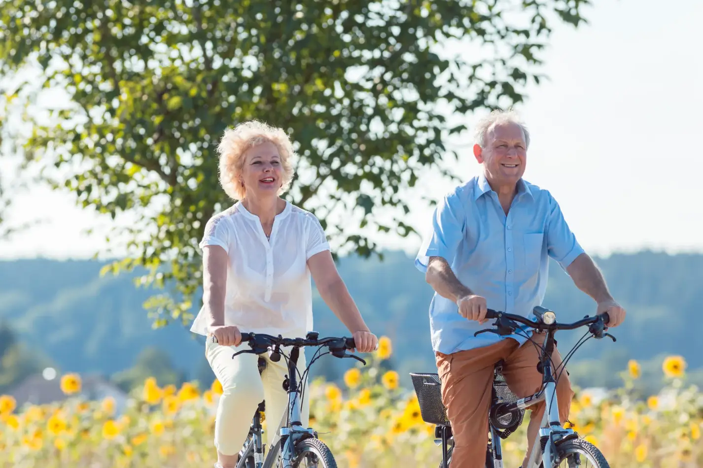two active agers biking together on a warm field